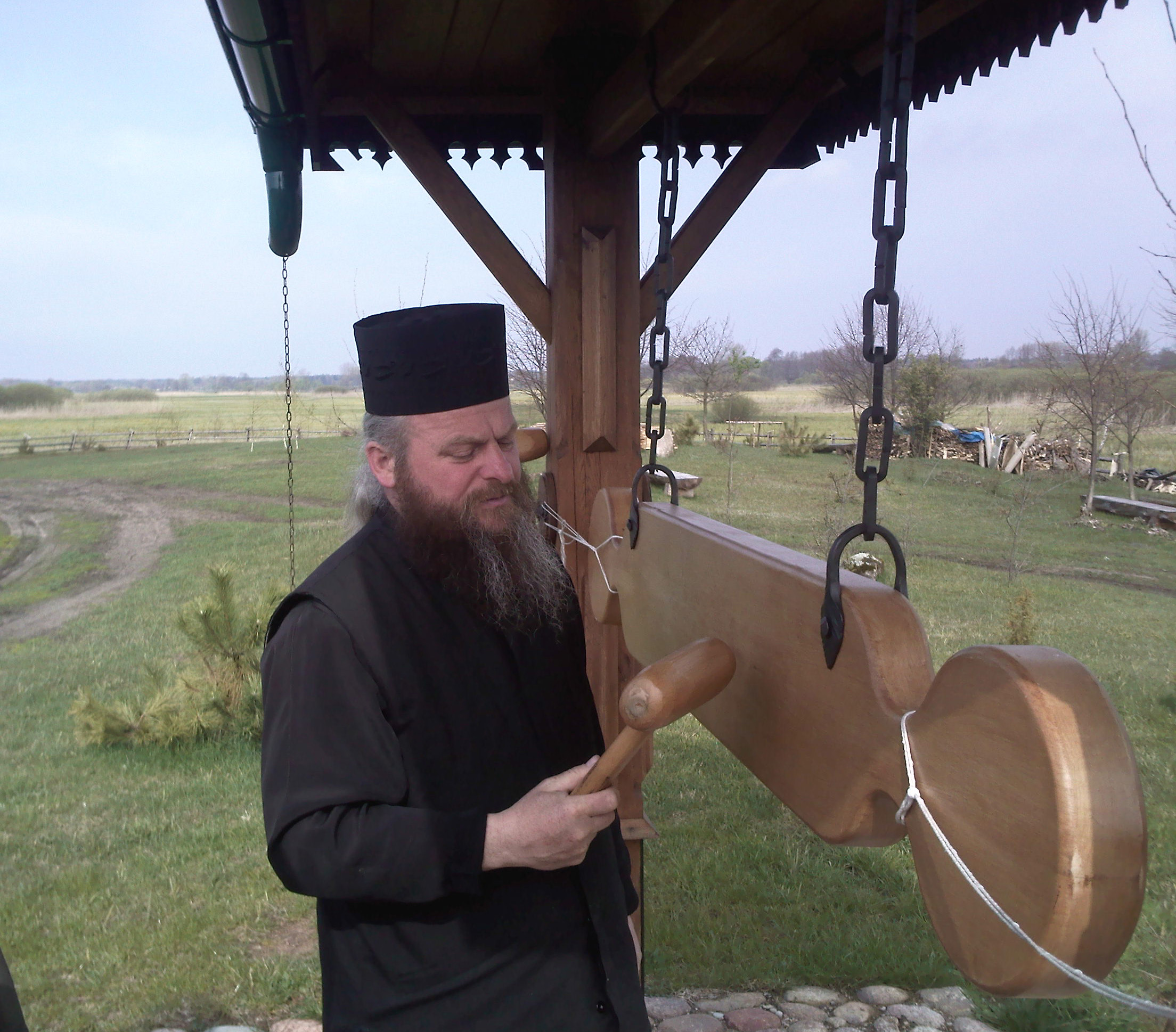 Archimandryta Gabriel (1962-2017) przy drewnianym dzwonie w skicie w Odrynkach, 2010 r. Wikipedia